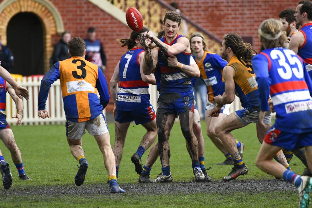 CONTESTED FOOTY: Muddy Gisborne midfielder Matt Goodyear fires out a handball against Golden Square. Pictures: NONI HYETT