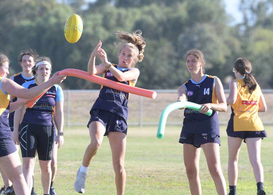 Abby Thompson disposes of the ball despite the attention at Bendigo Pioneers' training. Picture: NONI HYETT