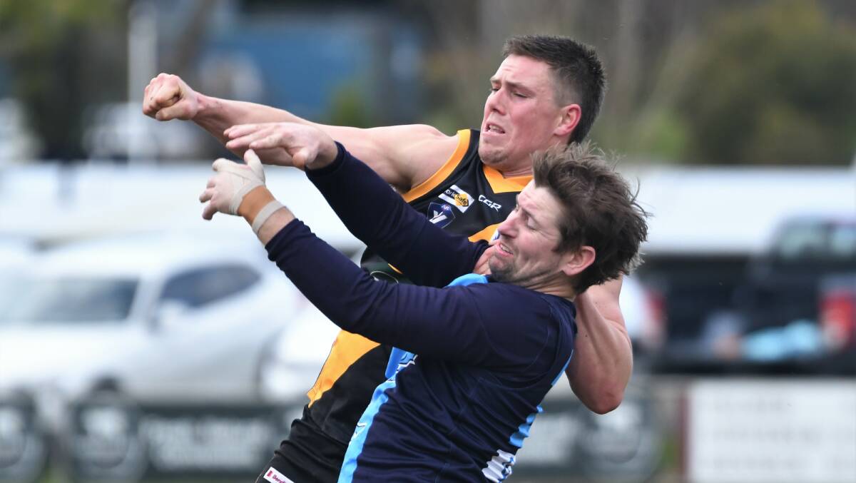 BATTLE: Kyneton defender Frazer Driscoll punches the ball clear of Sean Williams. Picture: ADAM BOURKE