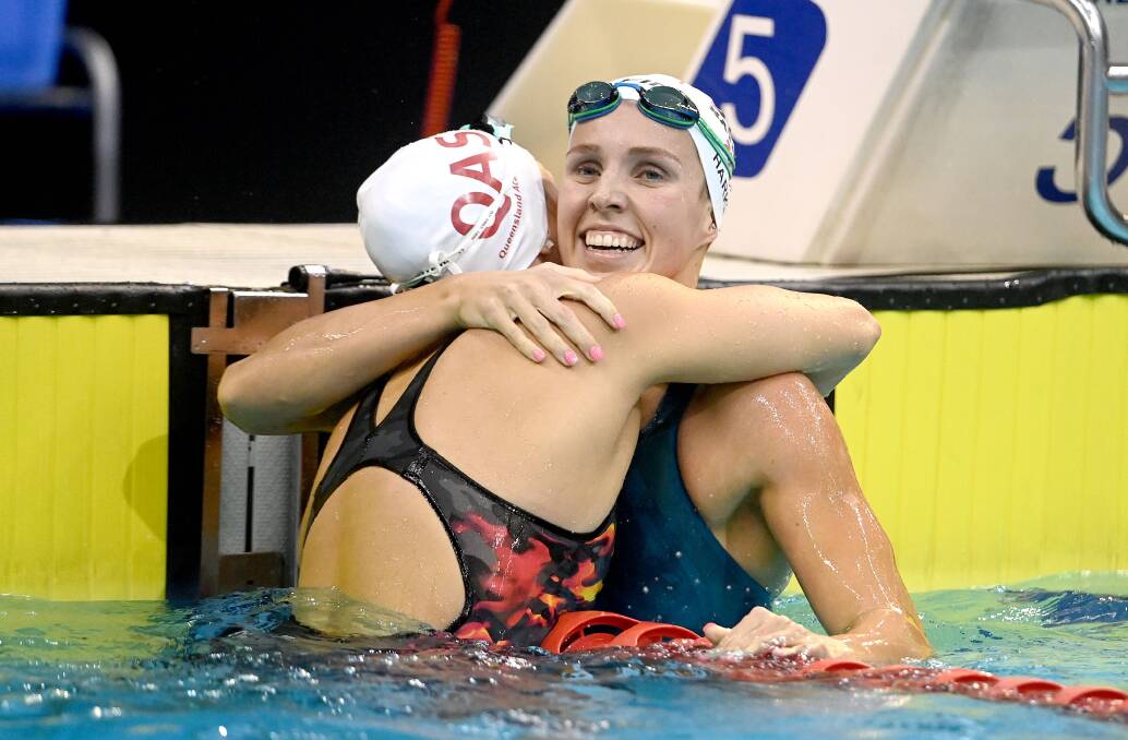 Jenna Strauch is embraced by Abbey Harkin after they finished first and second in the 100m breaststroke final. Picture: DELLY CARR