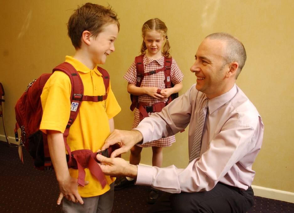 Chiropractor Dr Brett Holulden adjusts the schol back packs of son Tom 7 and daughter Olivia 6. Pic Brendan McCarthy 