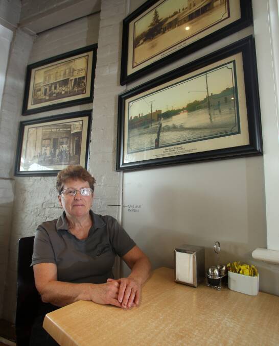 BOUNCING BACK: Bridgewater Bakehouse's Rae O'Toole in front of the flood marking in the store, along with a picture of the 2011 floods. Picture: PETER WEAVING