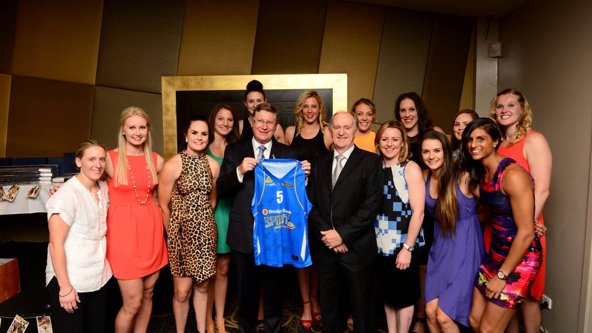 Premier Denis Napthine proudly holds a signed singlet as he stands with the Bendigo Spirit players and coach Bernie Harrower. 