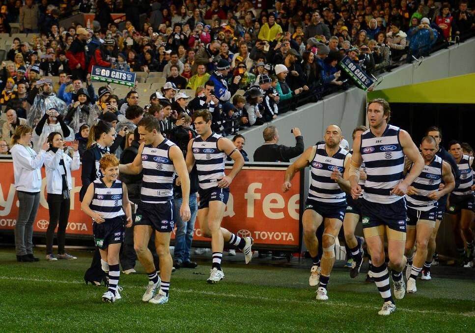 Col runs onto the MCG with Geelong skipper Joel Selwood and his team-mates last year. Picture: AFL
