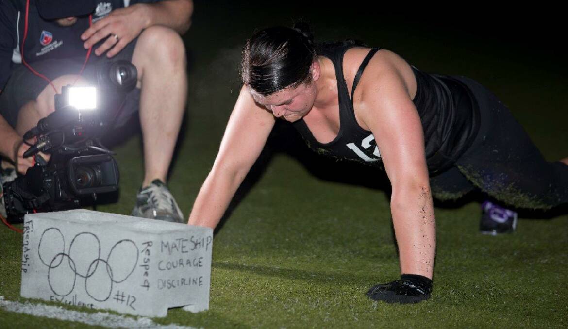 Tegan shows strength and focus during a boot camp exercise. Her concrete block bearing her candidate number and the Olympic ideals can also be seen.