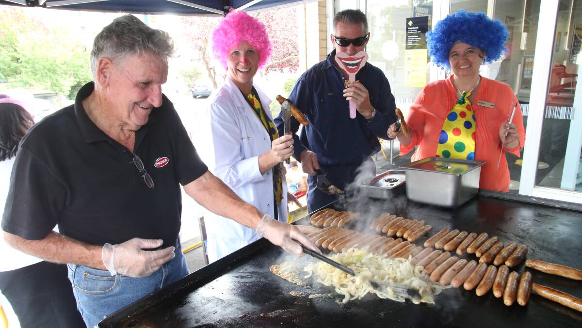 Clown bankers Jacki Leed and Michelle Kelly with Eaglehawk Lions Club BBQers George Martin and Tony Harrison. Picture: PETER WEAVING