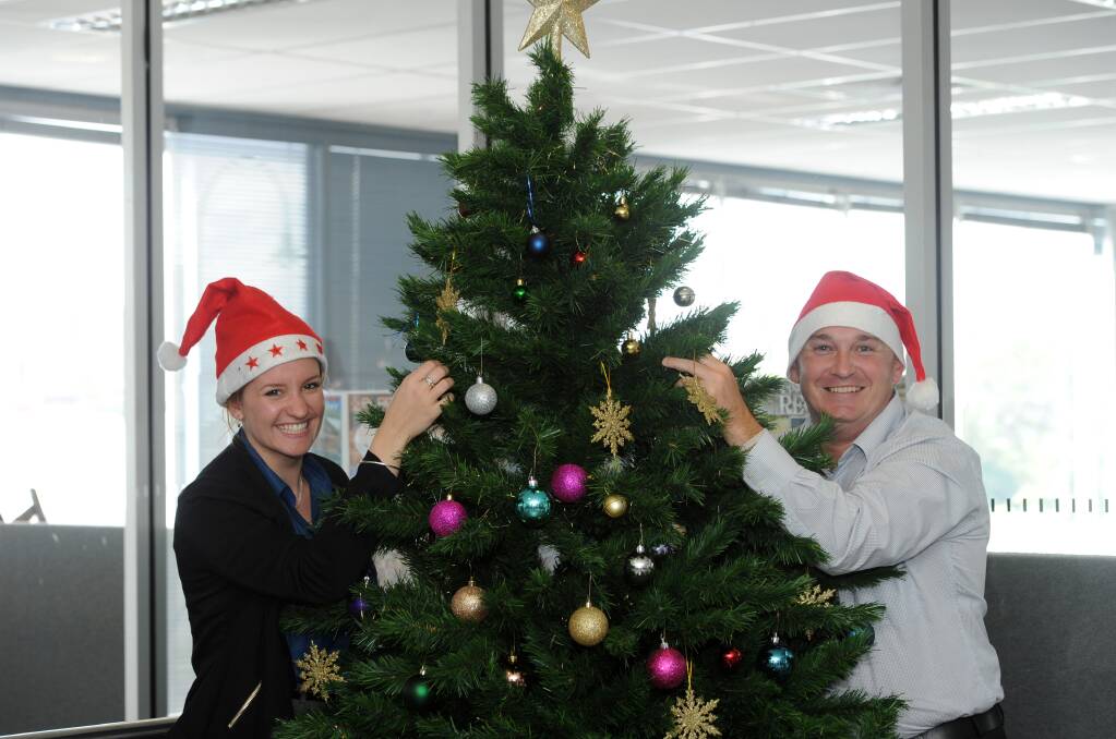 DECORATING: Bendigo Advertiser intern Kate Witherby and graphic designer Aaron Stewart decorate the tree in the office. Picture: JODIE DONNELLAN 
