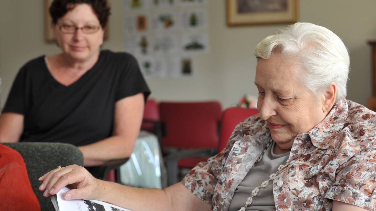 Nessie Baird looks at old photographs while staff member Sherry Taylor looks on. Picture: JODIE DONNELLAN 
