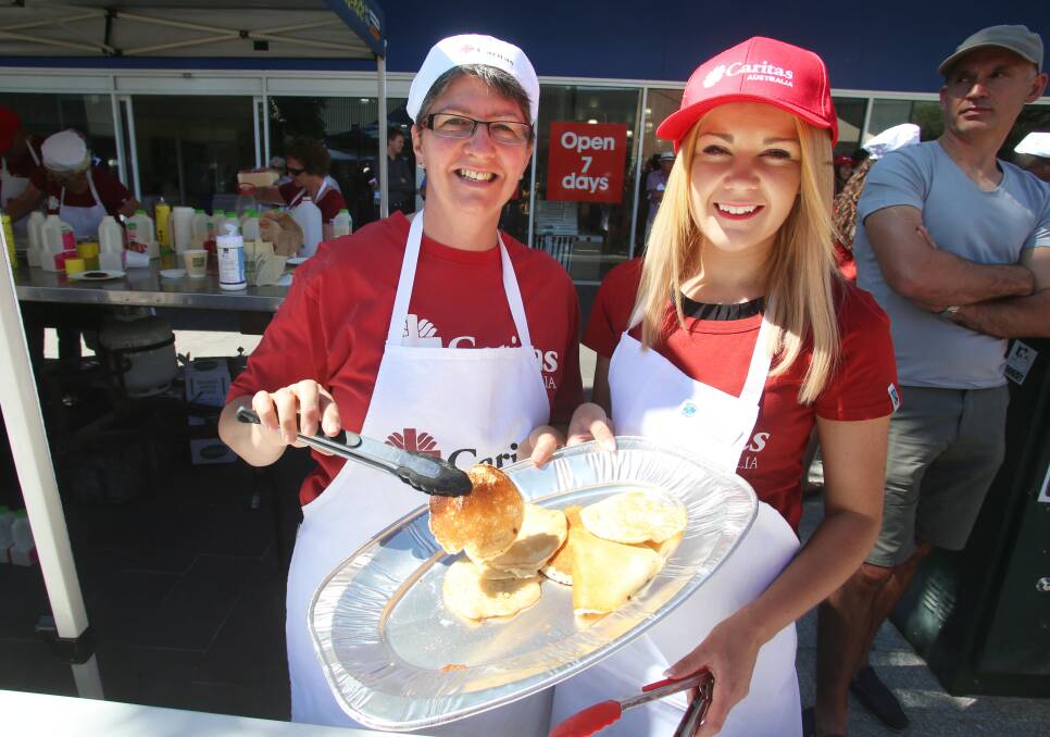 Helen Mewburn and Cara Lewis moving the pancakes. Picture: PETER WEAVING