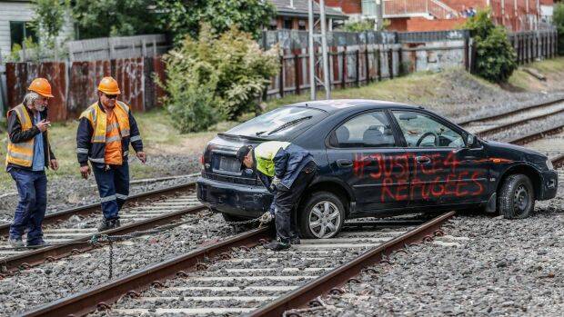 Workers prepare to tow the protesters' car from the tracks at Ascot Vale. Photo: Jason South
