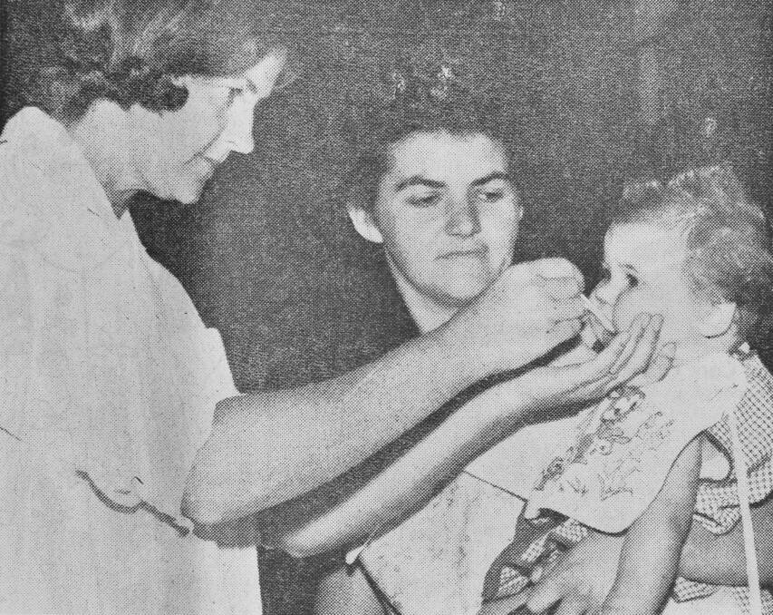 Sister Bonney gives a dose of Sabin vaccine to Jan Semmens and in the background is Mrs Dot Semmens.
