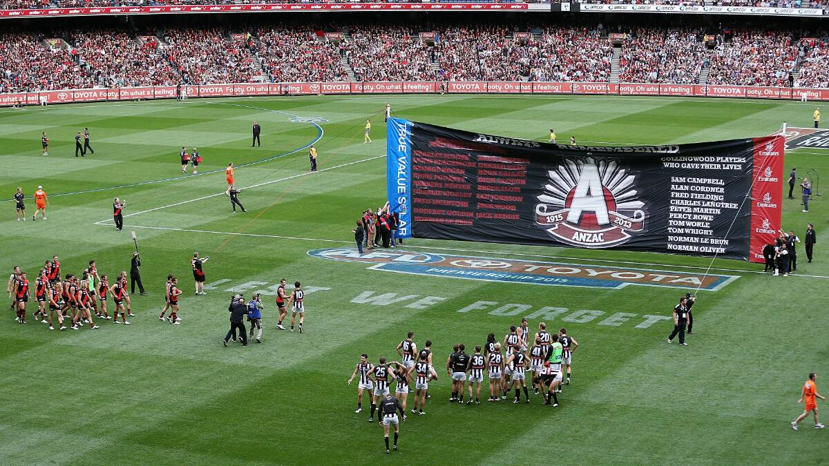HISTORIC DAY: Collingwood and Essendon teams run through the banner during last year's Anzac Day clash. Picture: GETTY