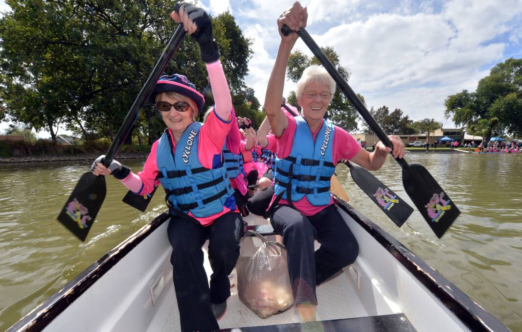 FIGHTERS: Jenny Curran and Sandra Albiston paddle out with Dragons Abreast Bendigo to place petals in the water in memory of those who have succumbed to breast cancer. Picture: BRENDAN McCARTHY