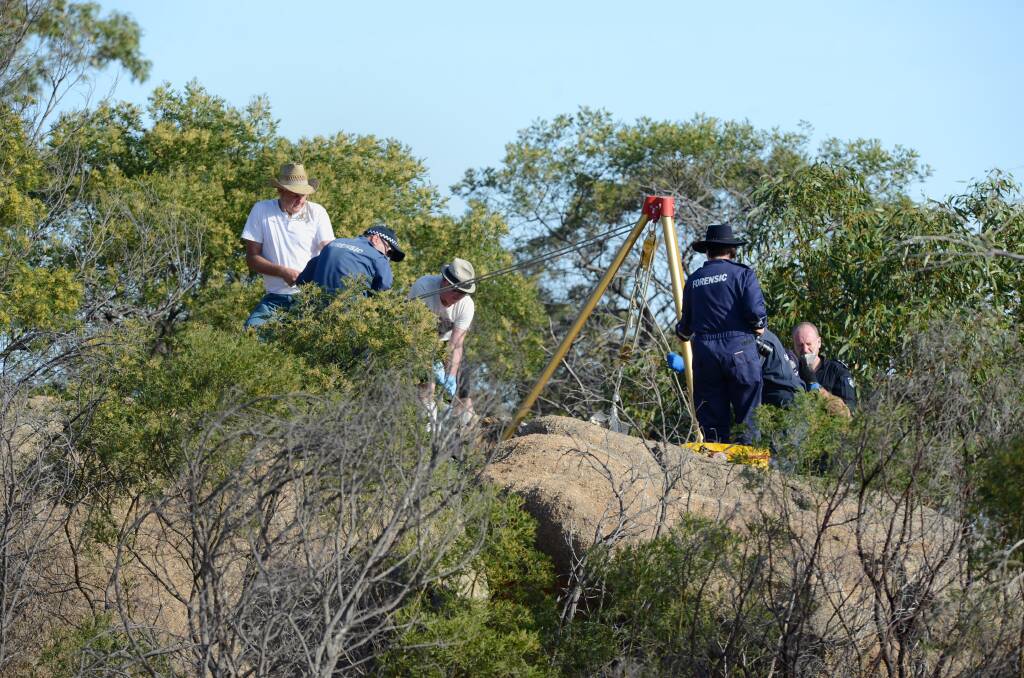 GRIM FIND: Police pull Wayne Amey's body from between two rocks on Mt Korong in December.