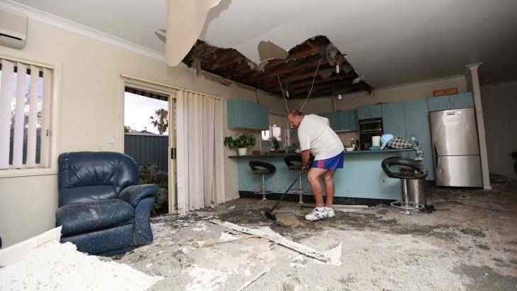 Frank Partlic cleans up rubble in his home. Photo: Cole Bennetts