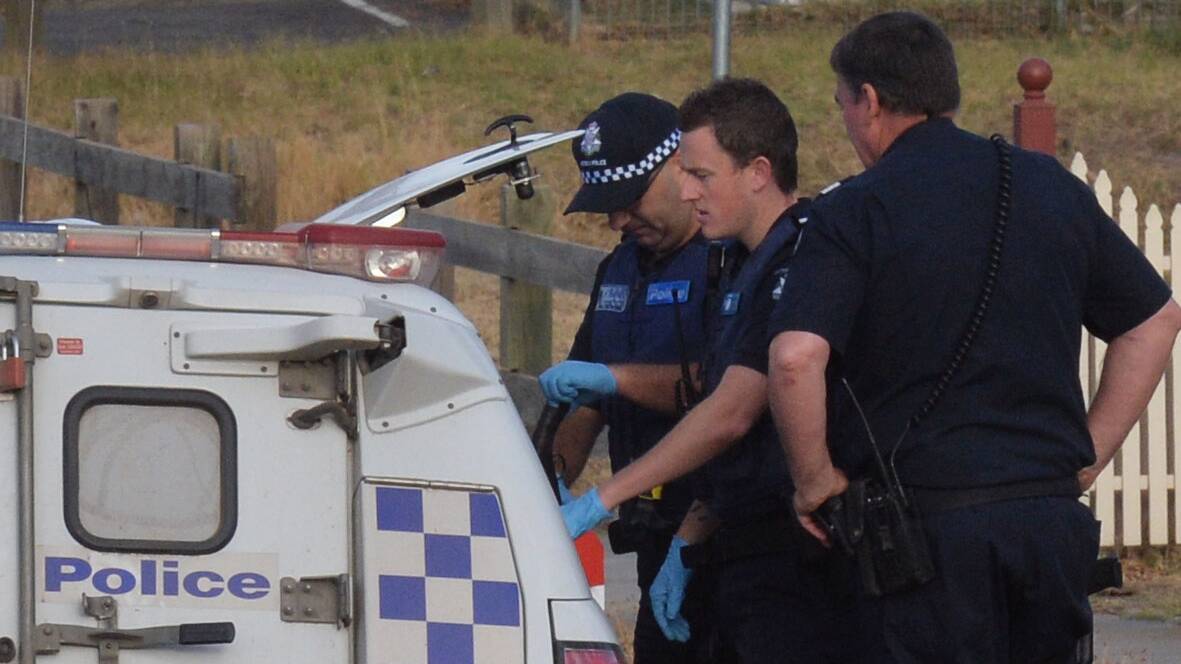 SEIZED: Officers place a weapon in a police vehicle. Picture: BRENDAN McCARTHY