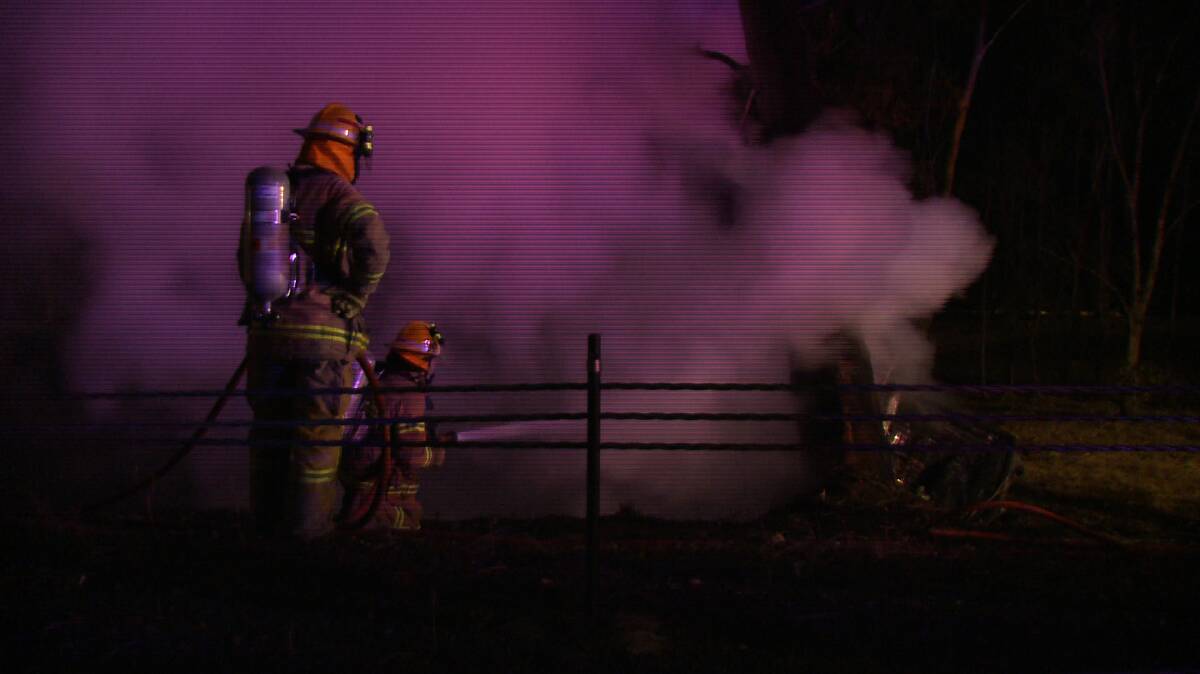 Firefighters douse flames at the scene of the accident. Picture: JULIAN FISHER