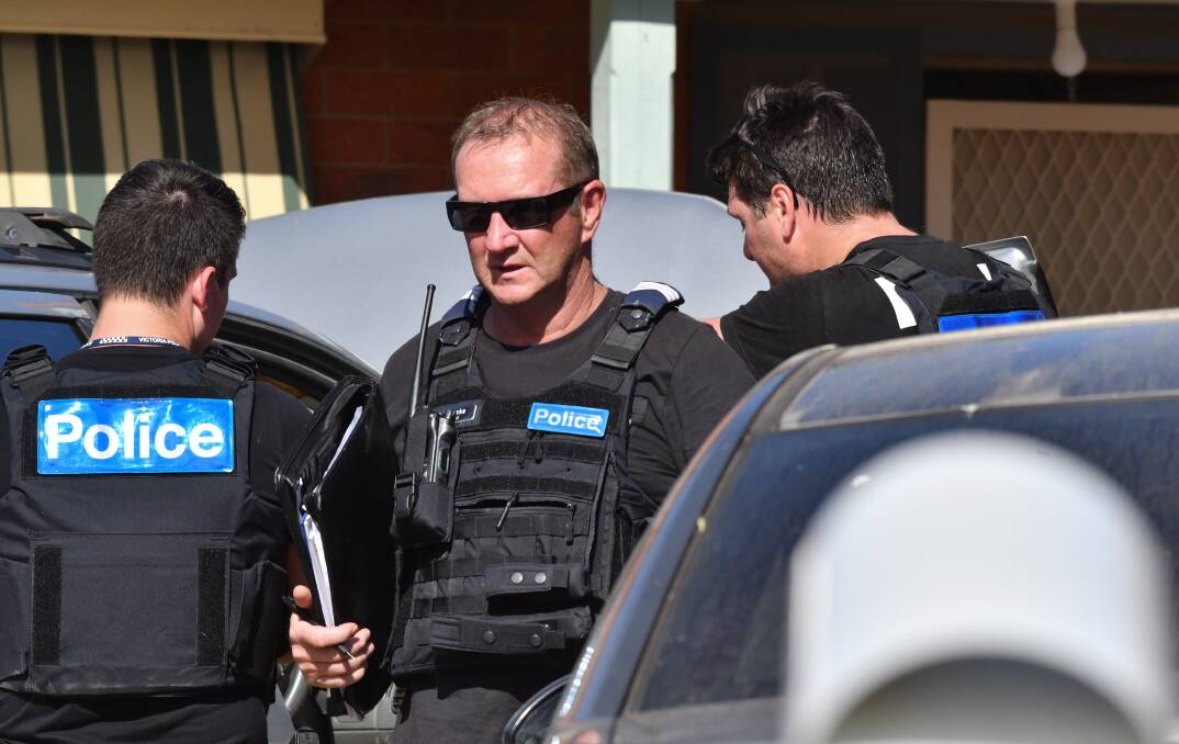 CHARGED: Officers after they arrested Aaron Burzacott at an address in East Bendigo on Wednesday. Picture: NONI HYETT