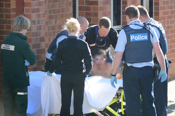 ARREST: Police and paramedics gather around a man who was arrested in West Bendigo yesterday. The man's face can not be shown due to legal reasons. 