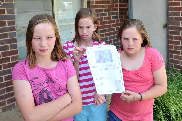 NOT HAPPY: Grace, Jessica and Olivia Murley with the ransom note left for their family after their Frosty the Snowman decoration was kidnapped from their Eaglehawk home. 