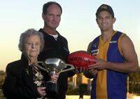 Thelma Ford holds the 1938 BFL premiership cup as Sandhurst's David Collins and Golden Square's Aaron Hawkins look on.