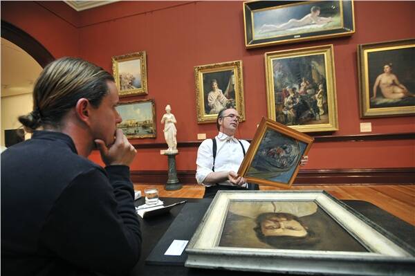 NOW LET ME SEE: Dr David Hansen, from Sotheby’s, examines Ross Smith’s painting Shawled Woman, by James Lawrence Isherwood, at yesterday’s valuation session in Bendigo Art Gallery.