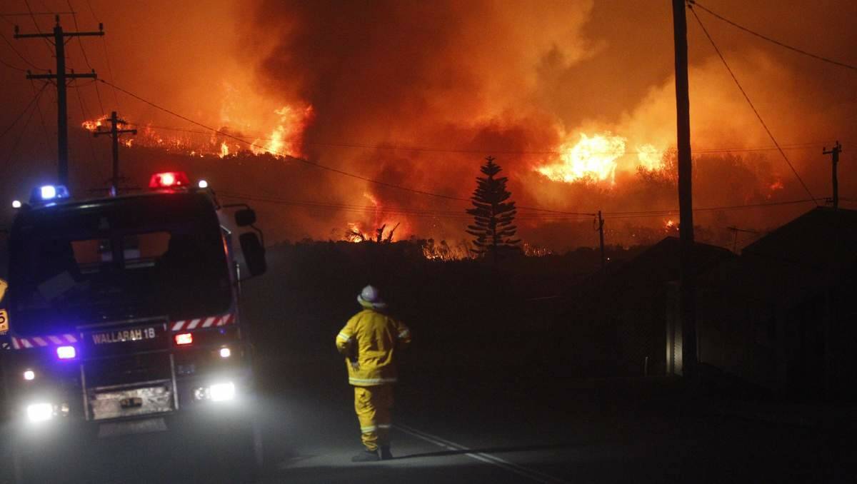 IN THE THICK OF IT: The huge blaze at Catherine Hill Bay surging towards fire crews.  Picture: Jonathan Carroll