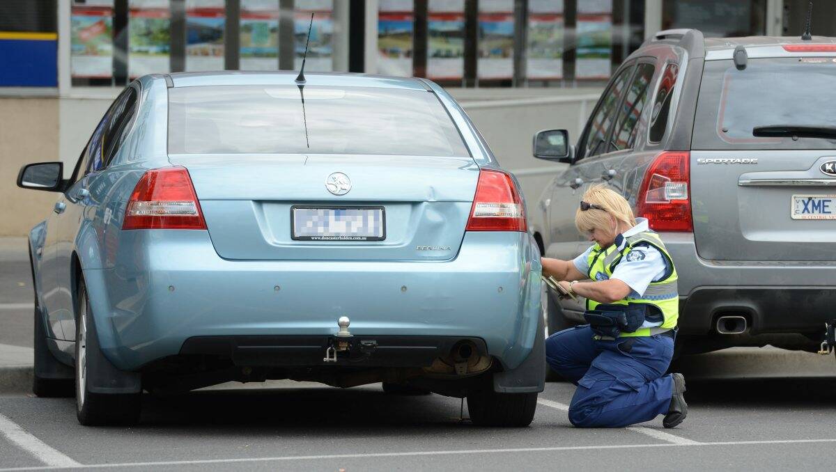 Caught out: A Sheriff’s officer clamps a car in Queen Street. Picture: Jim Aldersey