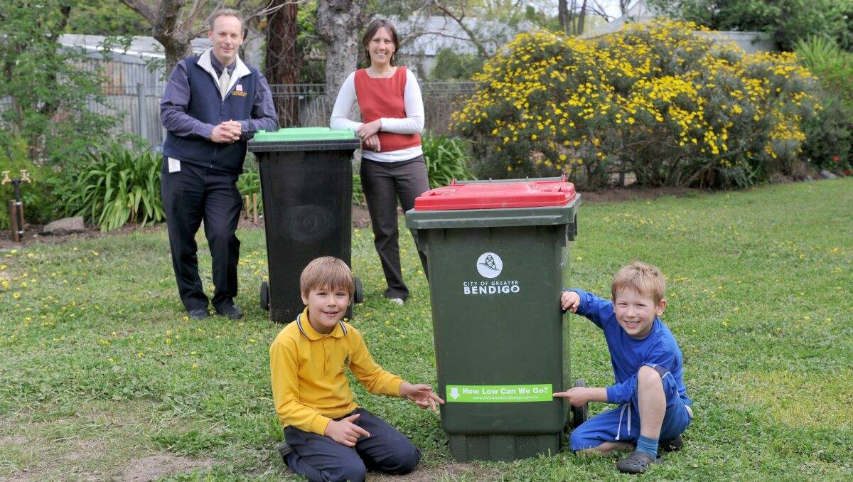 clean: Chris and Karen Corr with children Aiden and Jeremey showing the “How low can we go?” line on their rubbish bin. Picture: JODIE DONNELLAN