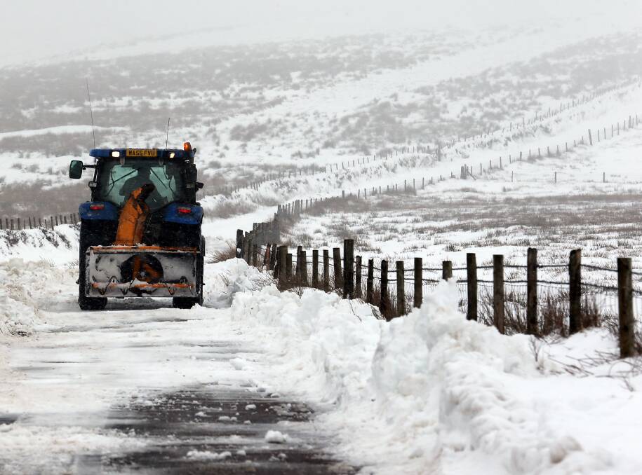 A tractor clears Snow covering a road besides fields near to Simonsbath in Exmoor, England. Photo by Matt Cardy/Getty Images