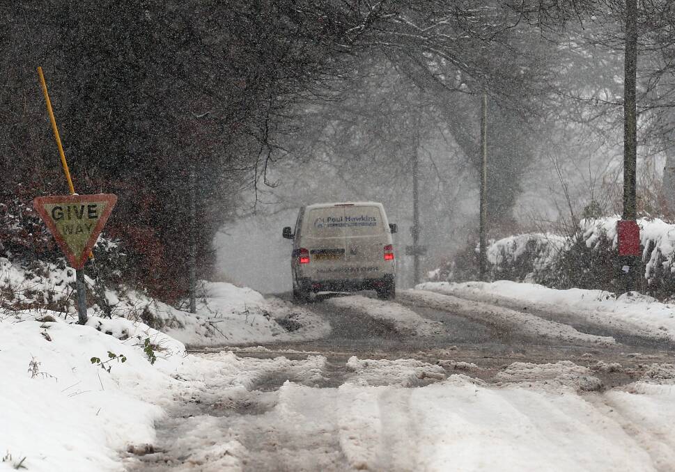 A van drives along a road as snow falls in Exmoor, England. Photo by Matt Cardy/Getty Images