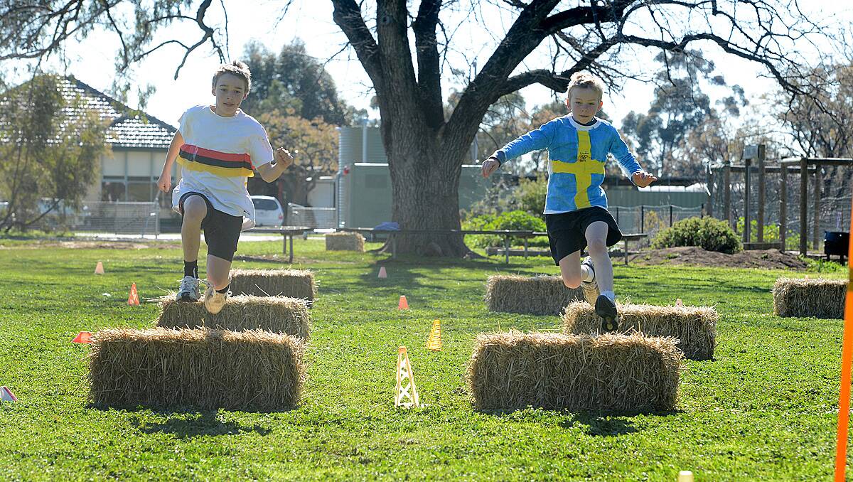 Charles Dole and Riley McNamara race in the hay hurdles at Goornong Primary School, dressed up in team colours for the schools mini Olympics. Photo Jim Aldersey