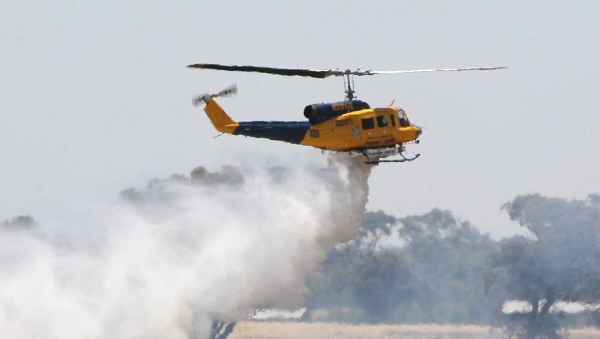 A water-bombing helicopter drops its load. Picture: File/Peter Weaving