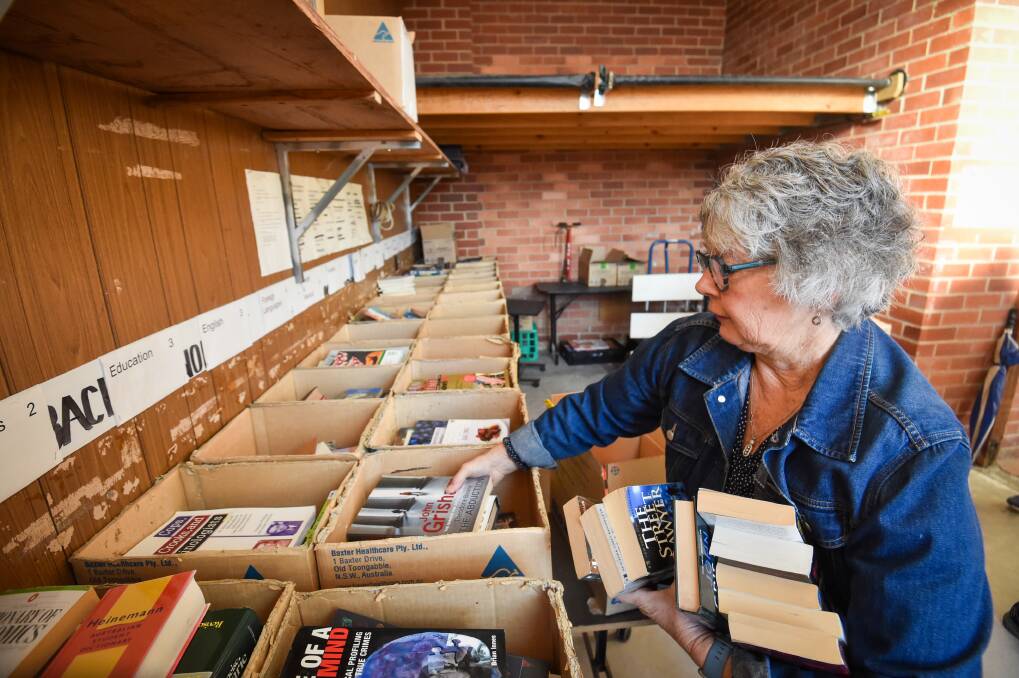 Book fair volunteer Kim Stewart sorting books out the back of Tom Tweed Stadium on Monday. Picture by Darren Howe.