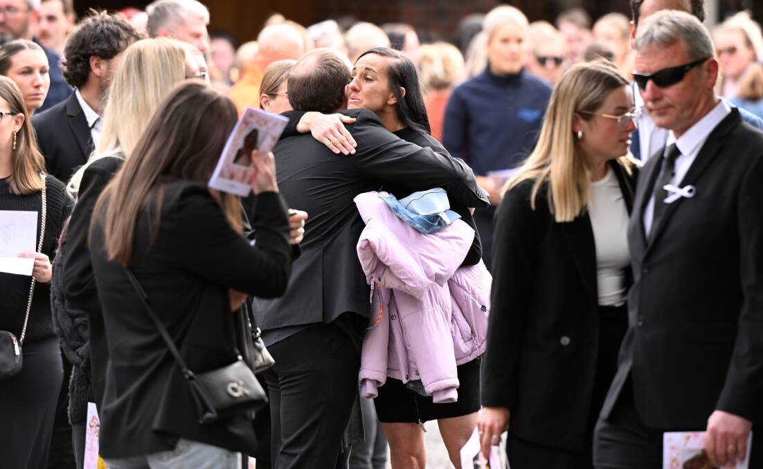 Mourners including Emma Faneco, a former teacher of Hannah McGuire's, embrace after the service. Picture by Adam Trafford